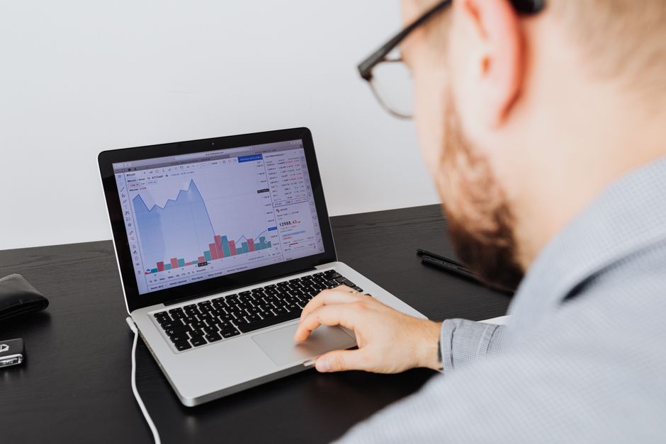 Analitičar radi na laptopu i pregledava financijske grafove