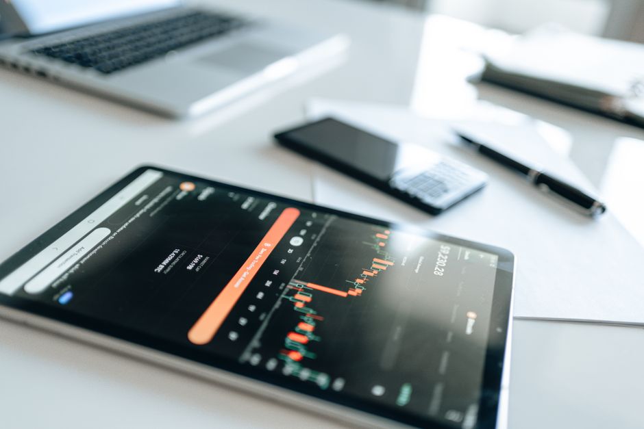 Moderni financijski alati uključujući tablet s tržišnim trendovima na bijelom radnom stolu